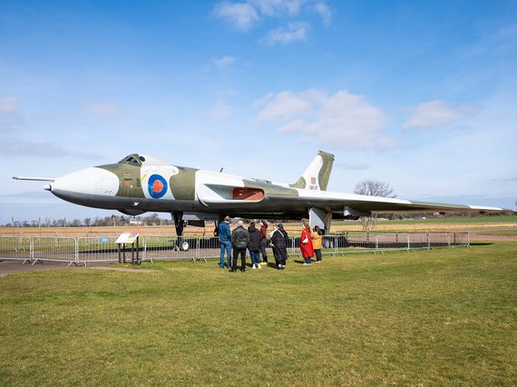 A group of visitors standing in an airfield next to a Vulcan aircraft