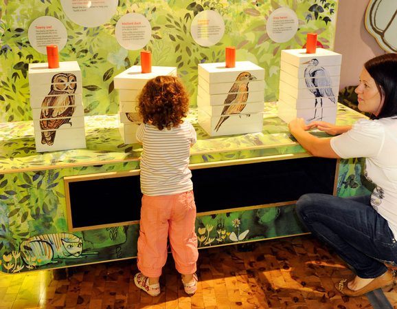 A mother and child interacting with a bird game in the Garden Detectives gallery.