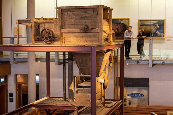 Two curators looking at a large threshing mill on display at the National Museum of Rural Life.