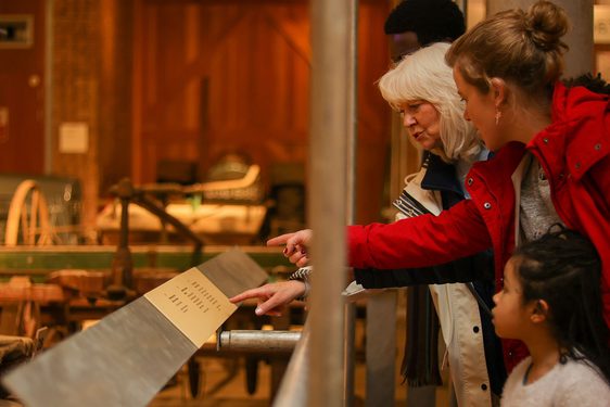 A family read a label in the tractor store at the National Musuem of Rural Life.