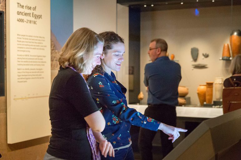 Two women looking at and using an interactive screen in a museum.