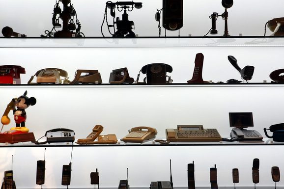 Rows of telephones and mobile phones from different eras.