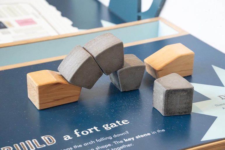 A selection of grey foam blocks piled between two wooden blocks. They are piled together to form a gate.