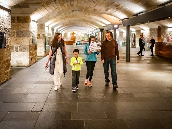 A family of four walk through a museum entrance hall with a low arched roof.