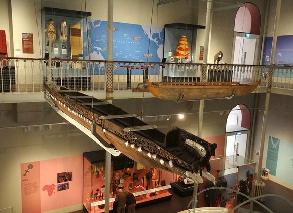 A canoe suspended from a ceiling in a museum gallery.