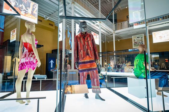 Three mannequins dressed in fashionable clothing: two standing in dynamic poses and one seated.