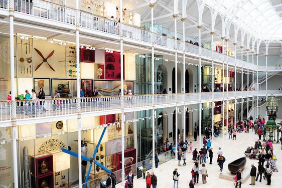 A multi-level open museum space with balconies and an arched ceiling. There are lots of visitors looking at objects on display.