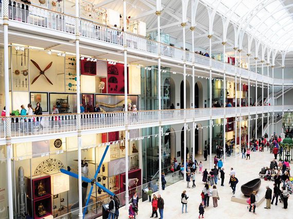 A multi-level open museum space with balconies and an arched ceiling. There are lots of visitors looking at objects on display.