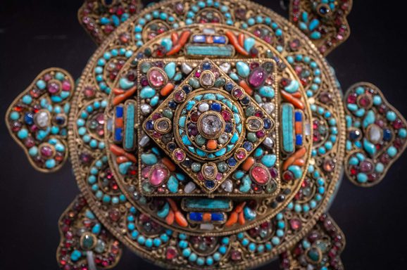 An ornament in the form of a Buddhist mandala, made from colourful glass and stones.