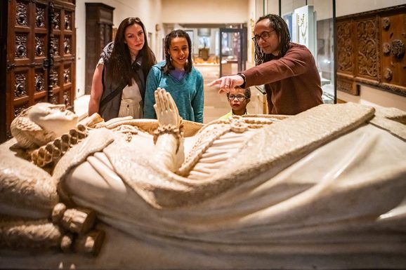 A family looking over a casket of Mary Queen of Scots.