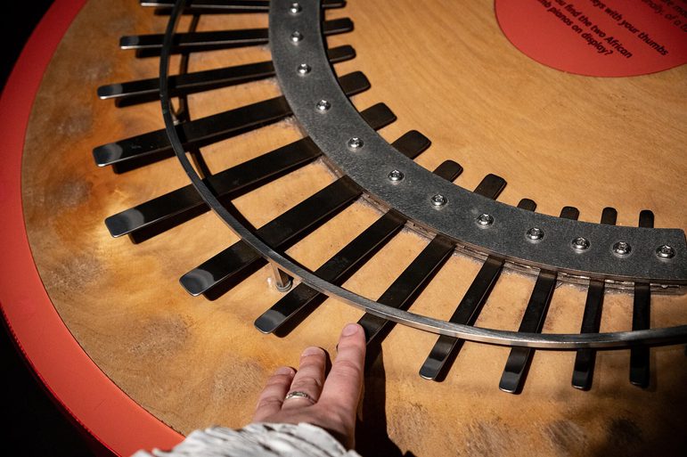 A wooden and metal thumb piano. A hand is playing one of the keys.
