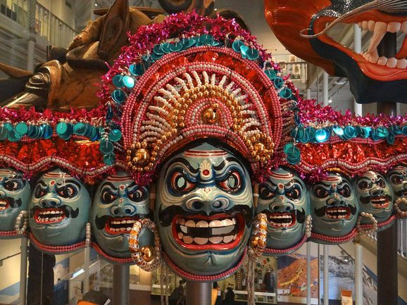 A row of colourful masks on display in a museum.