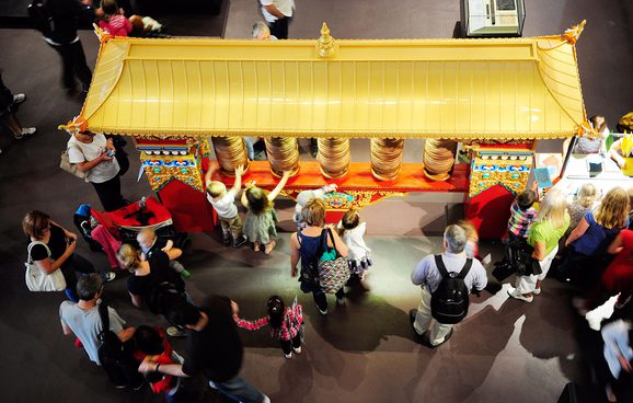 Visitors interact with the Tibetan prayer wheel, on display on Level 1 in the Living Lands gallery