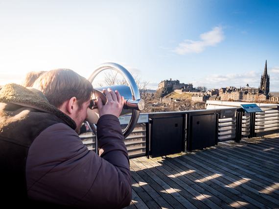 A visitor viewing the landscape of Edinburgh through a tower viewer on the rooftop terrace.