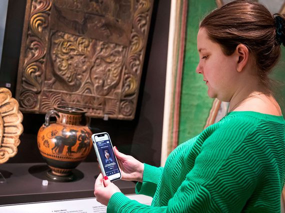 A visitor looks at their phone infront of a display case.