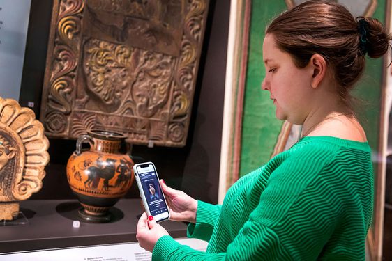 A visitor looks at their phone infront of a display case.