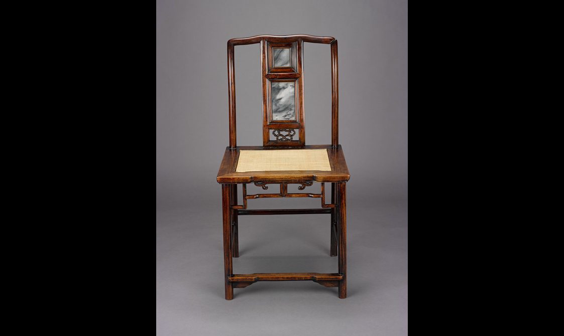 A decorative dark brown-red wood chair with a light yellow fabric in the middle of the seat