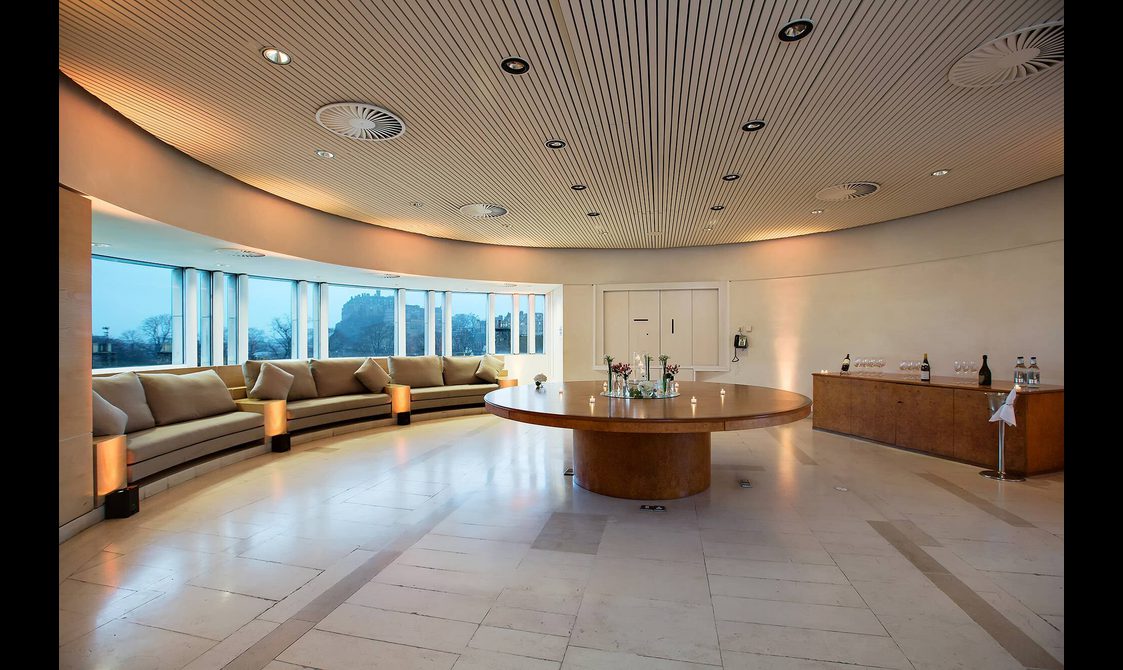 A circular board room with white walls and curved windows.