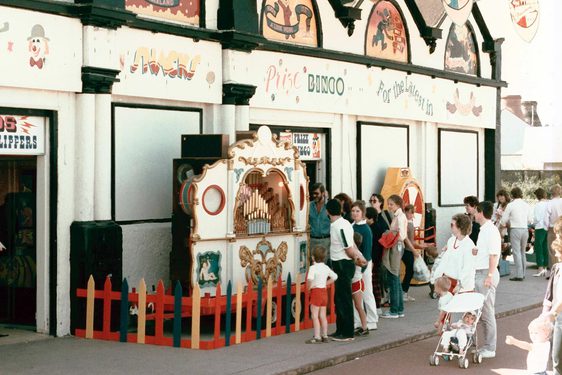 The outside of a seaside arcade with people lining up outside.