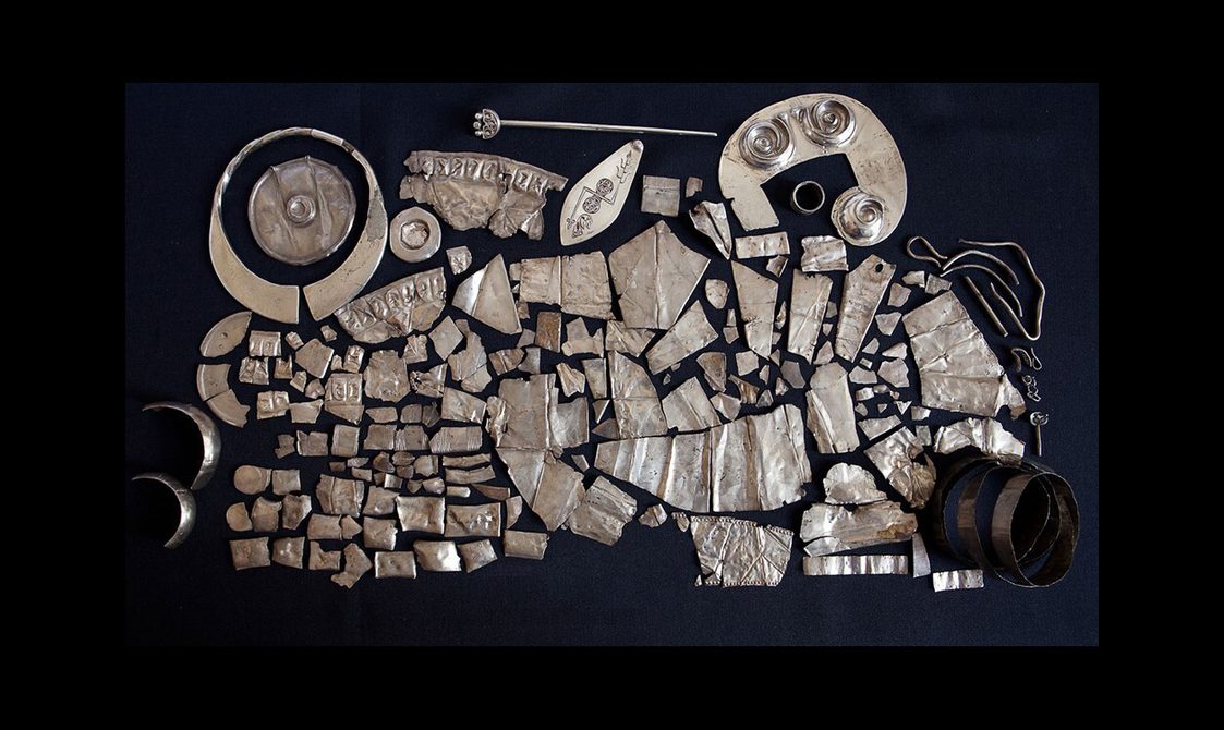 A spread of multiple differently shaped and sized silver objects set against a dark blue background