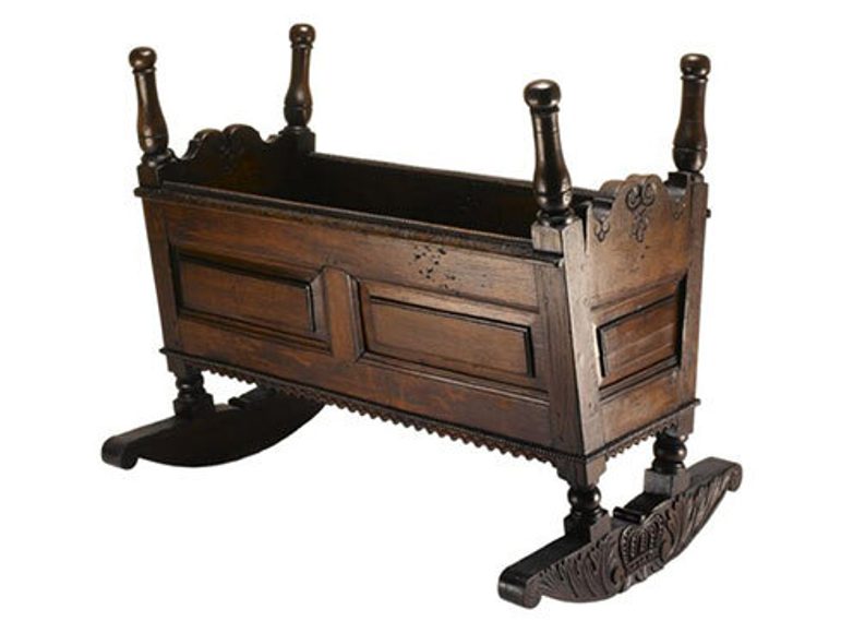An oak baby cradle with four legs protruding from each corner