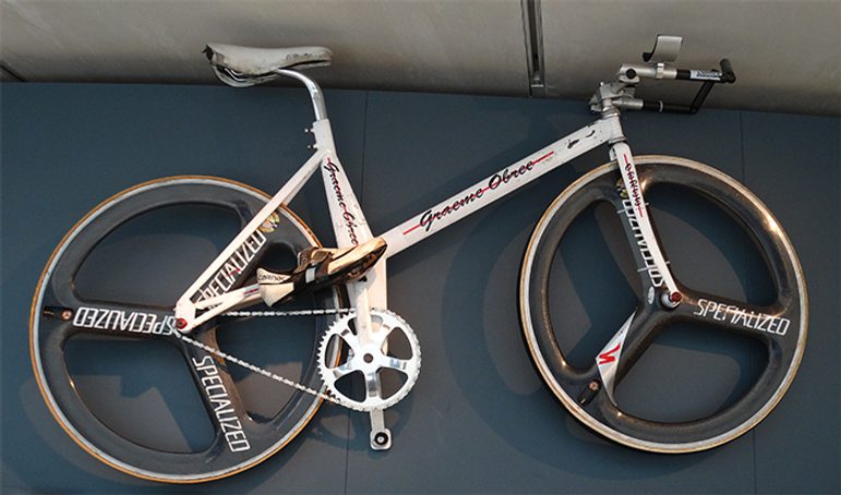 A white bicycle mounted on a dark grey wall.