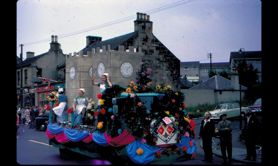 A float from Hartwood Hospital featuring a tribute to the building's distinctive double clock towers. Nurses are waving to the crowd on the gala parade