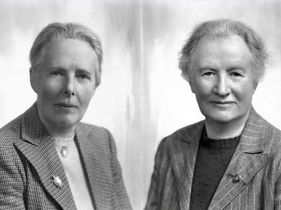 Two women with short hair wearing blazers and jumpers looking to camera placed side by side
