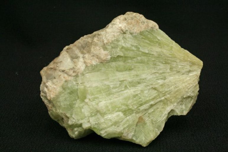 A pale green rock with an outer pinky edge against a black background