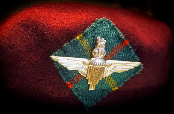 Close up on a red parachute regiment cap with a winged badge on a tartan patch.
