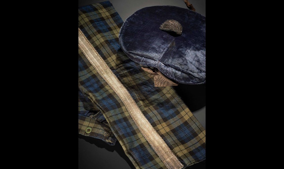 Close up of a navy Scottish bonnet and a navy and green tartan sash.
