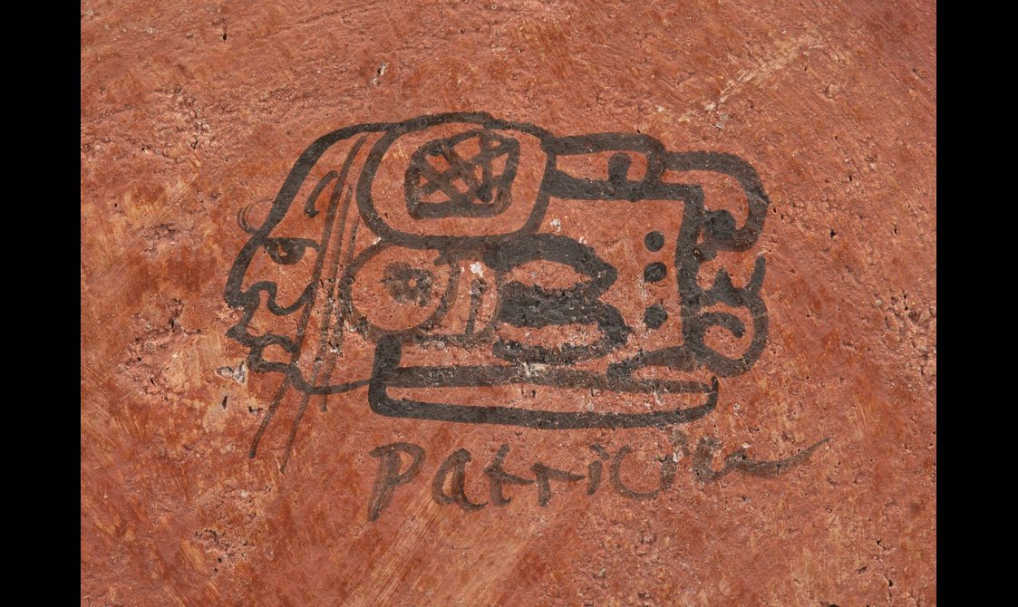 Artist's glyph showing an intricate, abstract designs on a red rock surface,