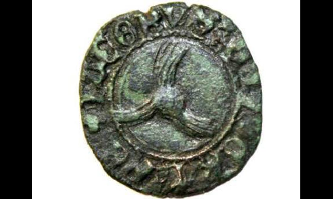 Circular disk with worn letters on the outer edge and a small circle with three curved lines radiating from the circle