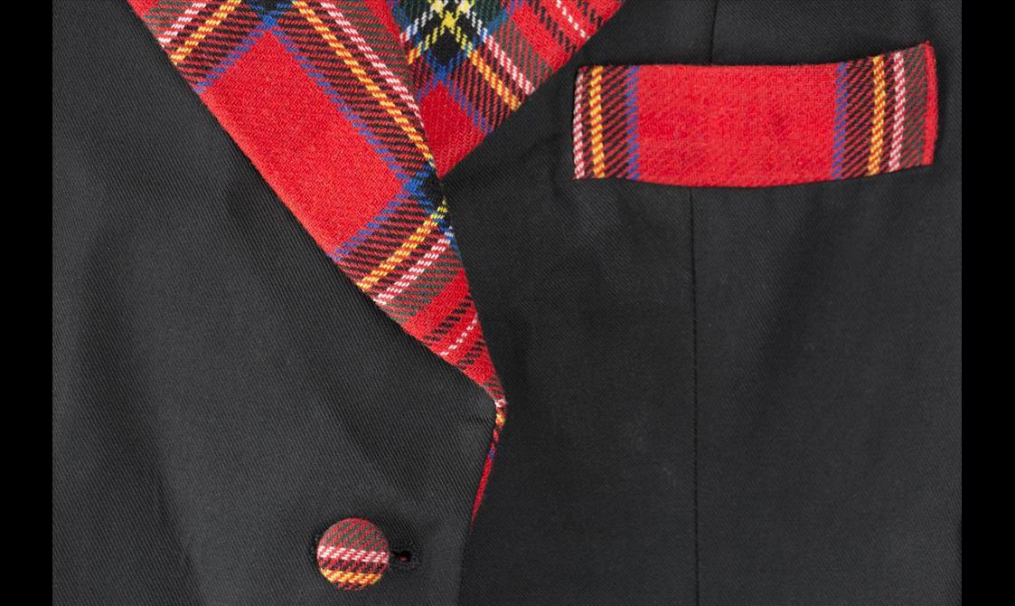 Close up of a black coat with red tartan lining and tartan buttons.