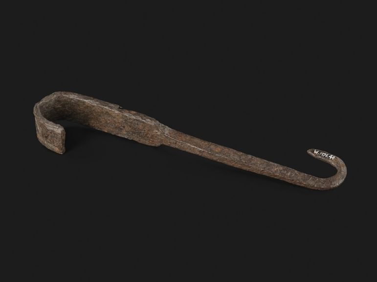 A somewhat rusted, and clearly used, iron rod with two hooked ends. The hooks go in opposite directions, like the points of the letter 'S'.