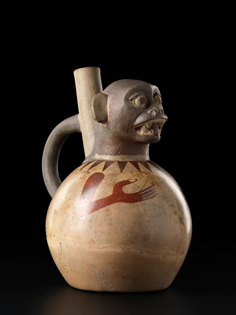 A rounded jug with a monkey's face at the top. A handle and spout are visible behind the monkey's head.