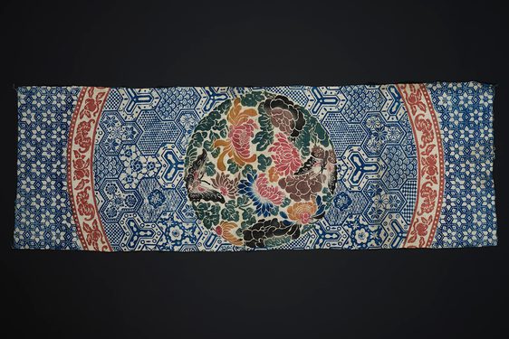 Colourful printed cotton with blue geometric print and a blue red and green selection of fruits and flowers in the centre.