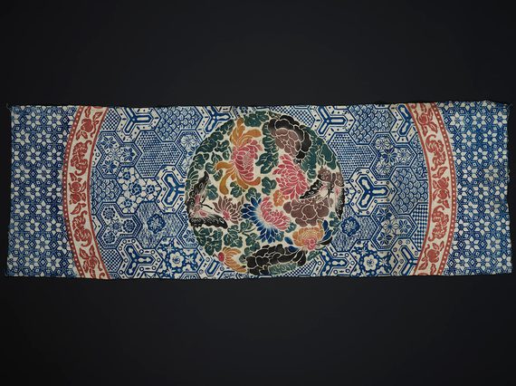 Colourful printed cotton with blue geometric print and a blue red and green selection of fruits and flowers in the centre.