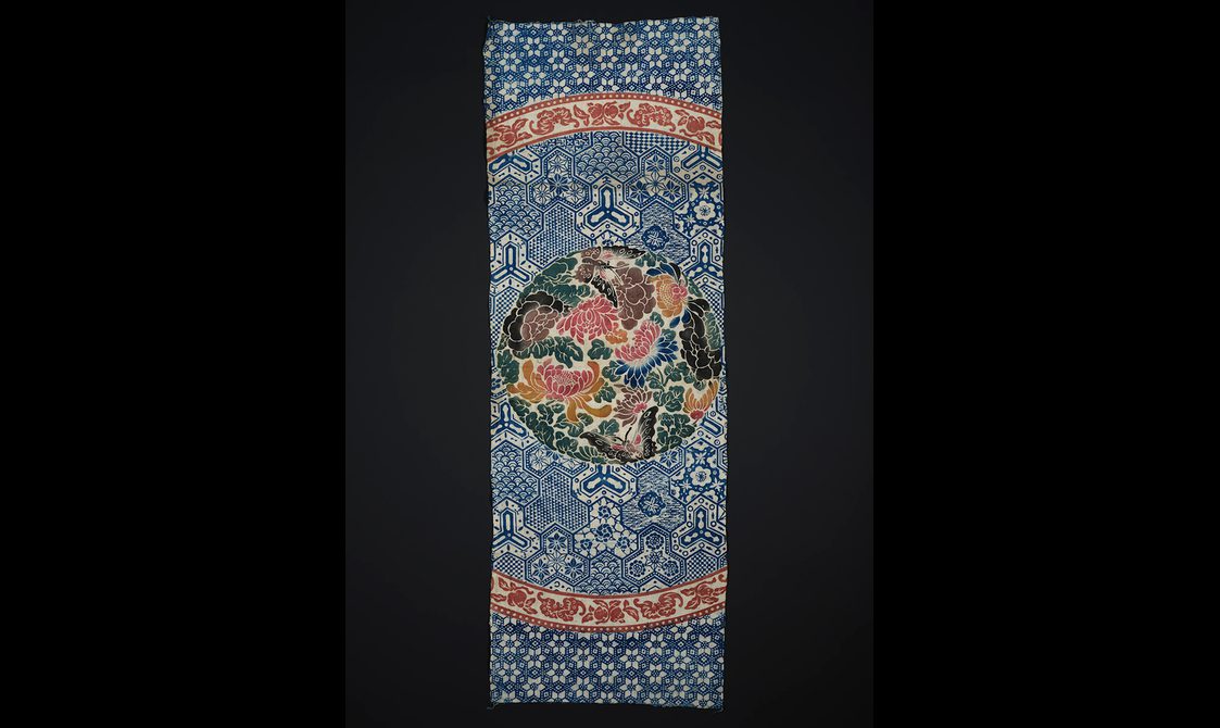 Printed cotton with intricate blue design and a circular section filled with colourful florals in pink, blue, green and orange.