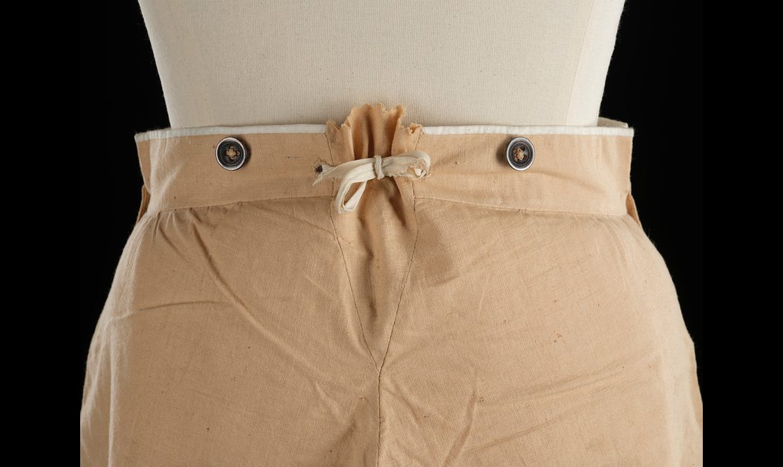 Pair of beige cotton men's trousers. Detail of the tie waist.