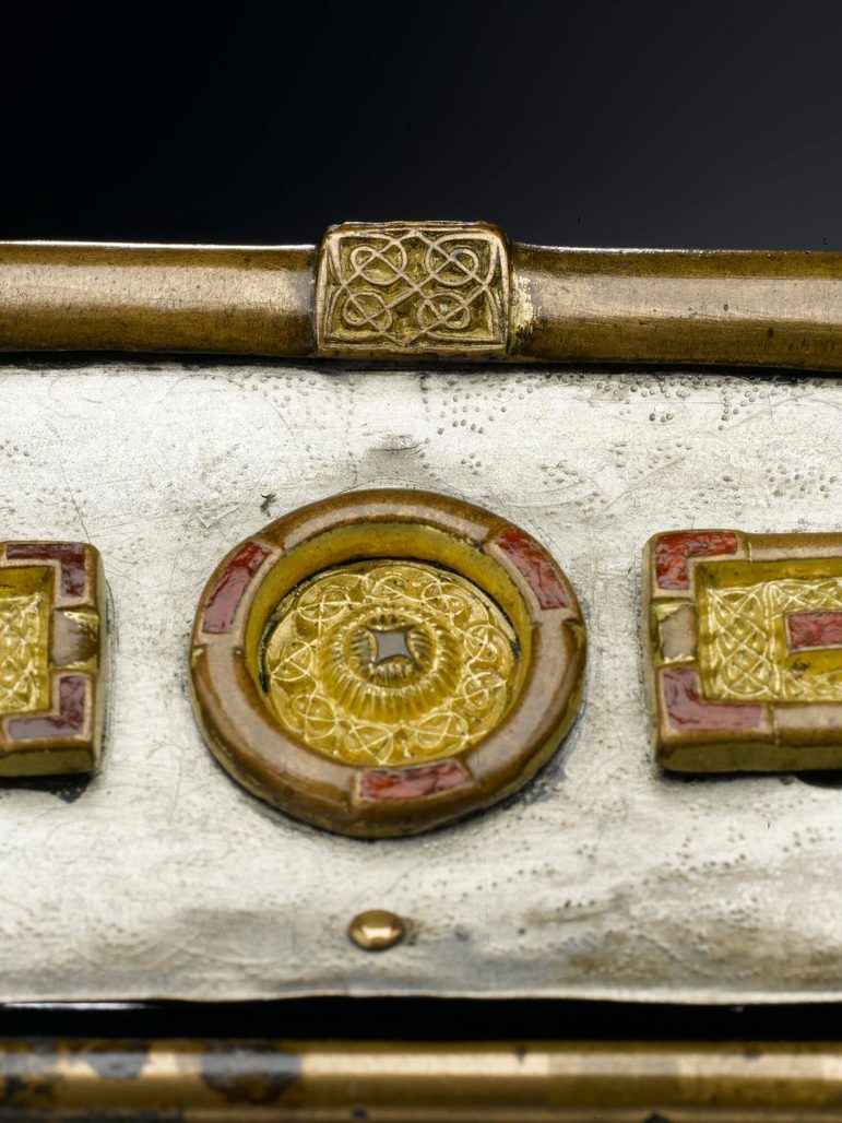 Close up of the roof of a small silver box. Panels on the box are engraved with interlaced designs.