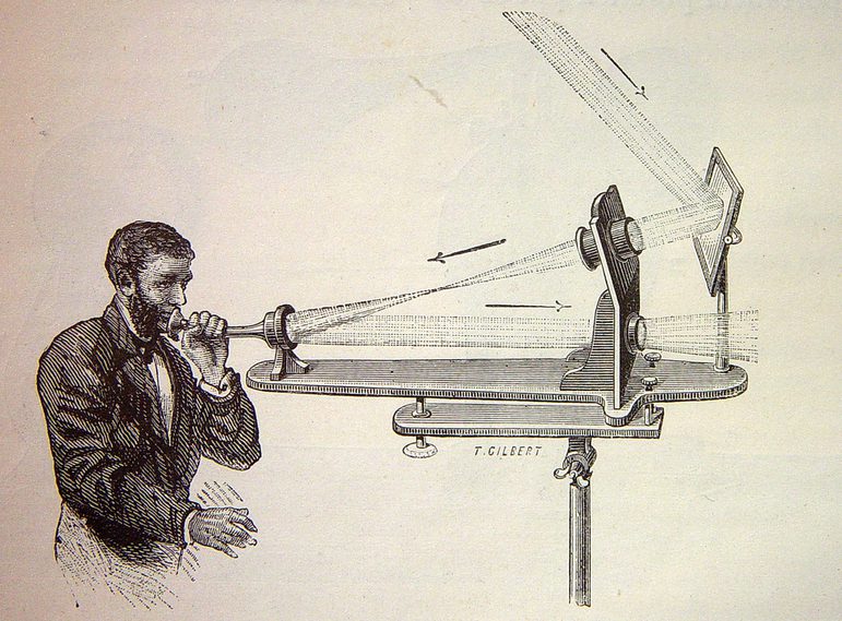 An illustration of a man with a beard wearing a white shirt and dark jacket speaking into a telephone like object