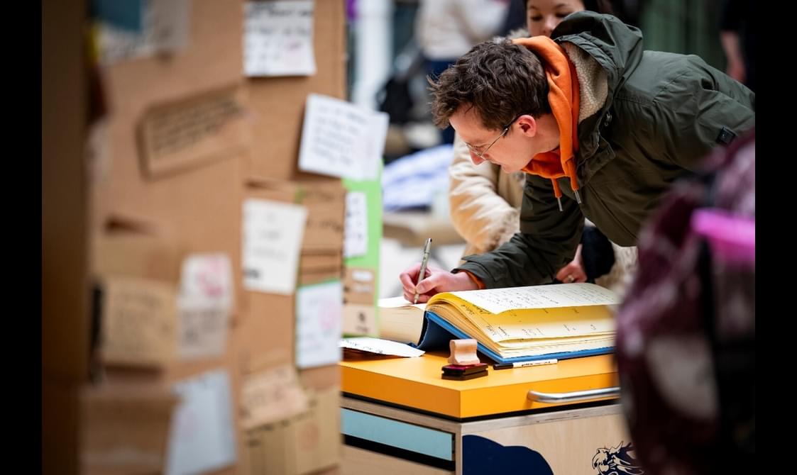 A person is writing in a book at the National Museum of Scotland.