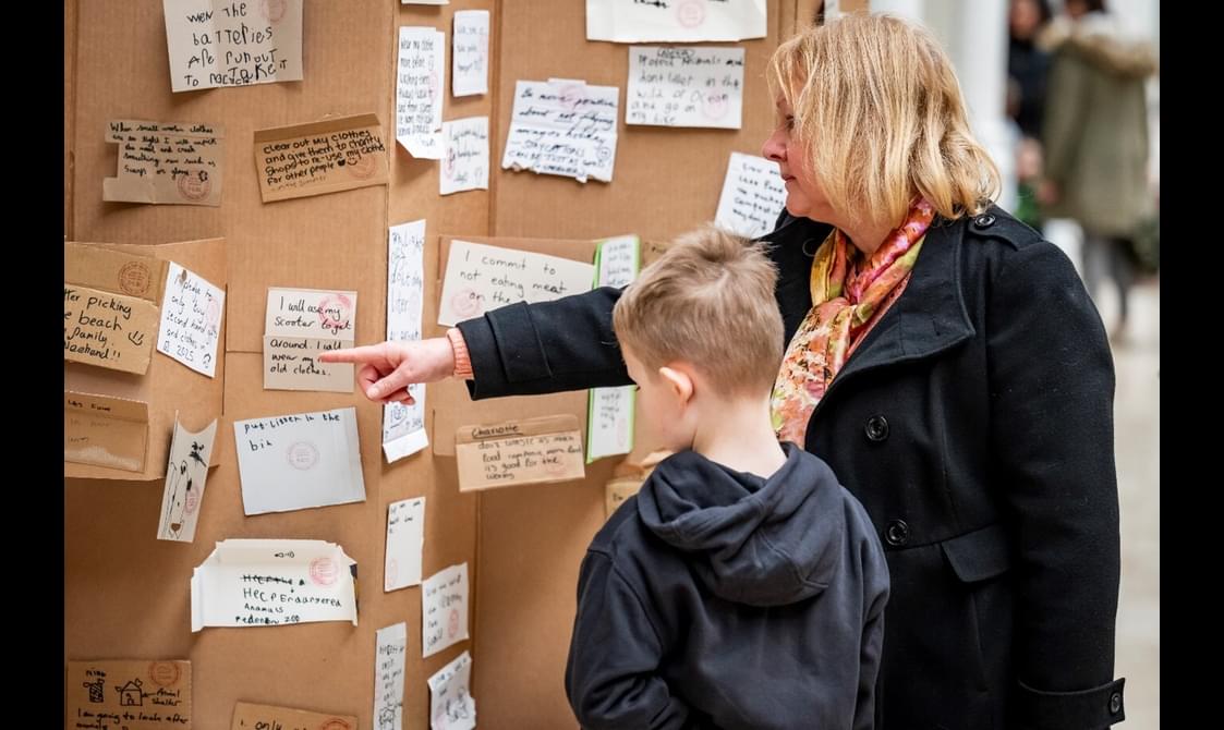 Two people are pointing at some notes written by visitors during a workshop.