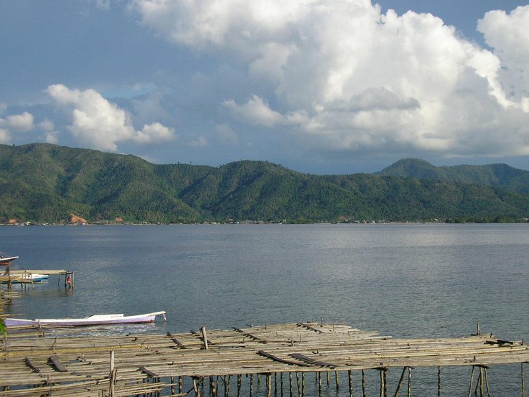 A view of green mountains framing a lake with a wooden dock in the foreground