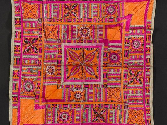 A square piece of pink and orange textile laid flat. It has intricate geometric patterns.