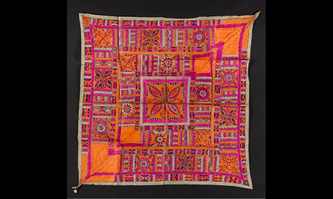 A square piece of pink and orange textile laid flat. It has intricate geometric patterns.