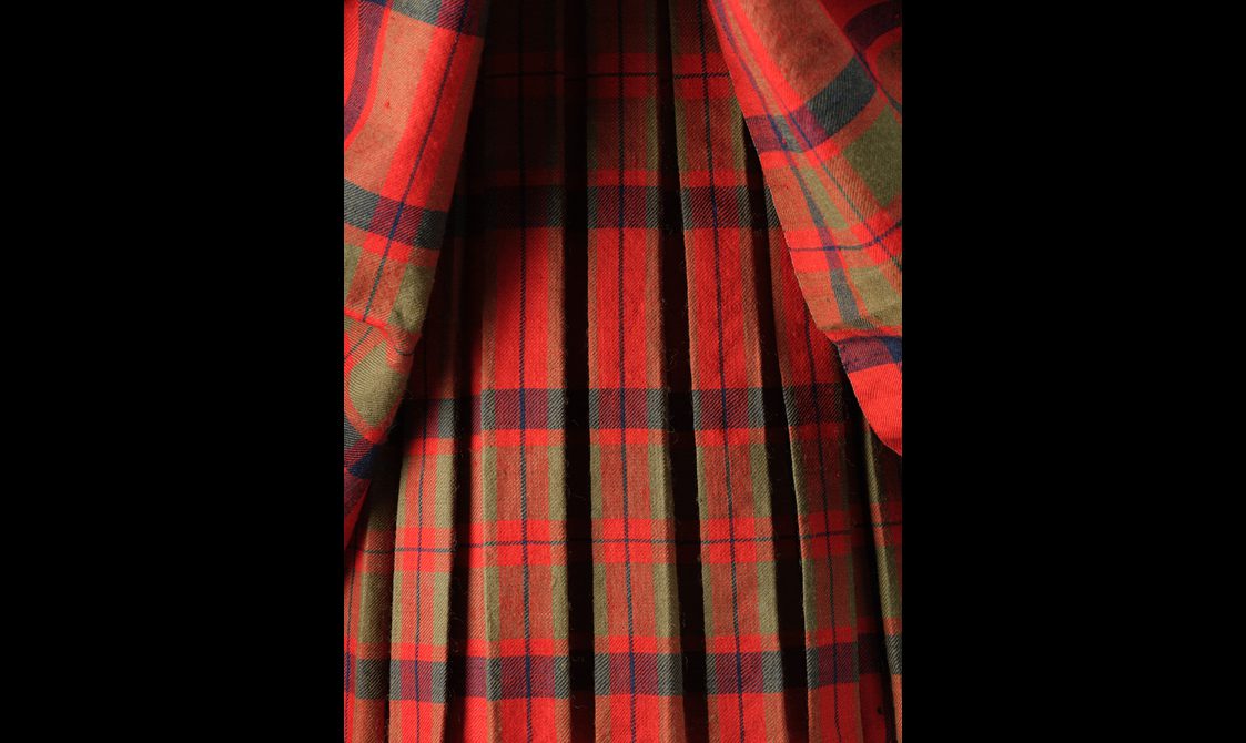 Detail of a pleated red tartan kilt.