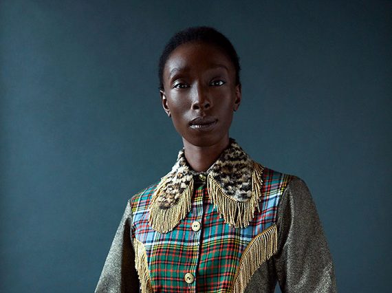 A woman poses in a patterned shirt and striped trousers
