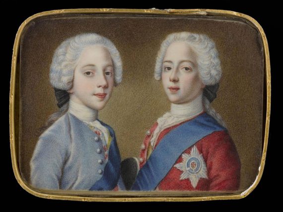 A portrait of two young men turned to one another sideways. The man on the left is wearing a white ruffle wig an a blue jacked with buttons. The man on the right is wearing a white ruffled wig and a red jacket with buttons, a blue ribbon draped over left shoulder and a six point star medal pinned to the coat.